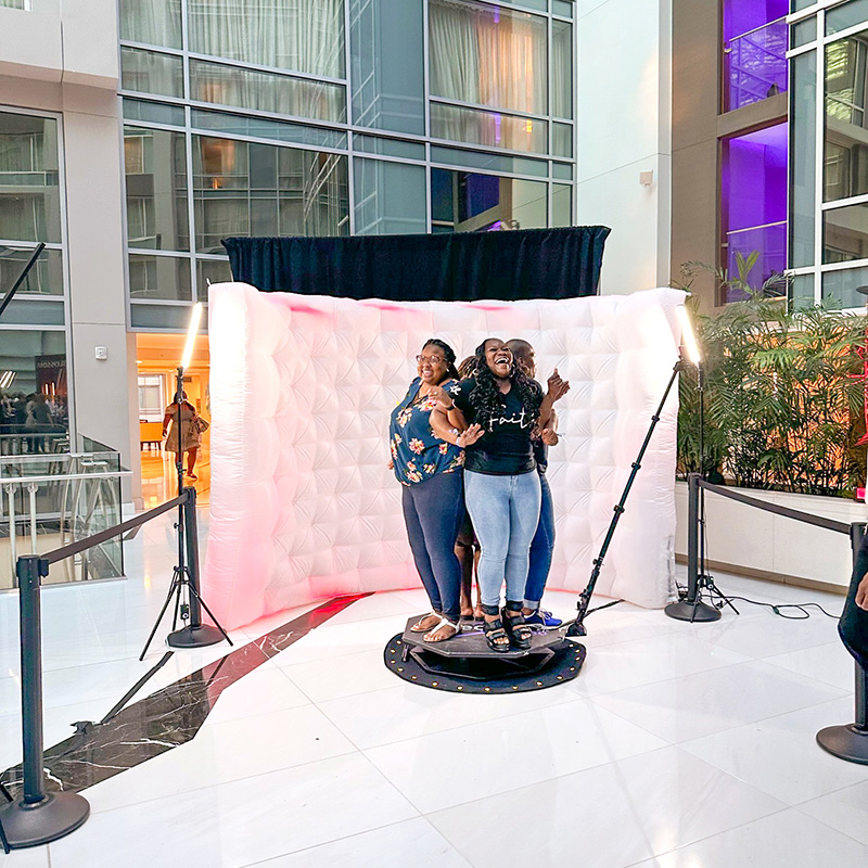 several women standing together laughing in a professional photo booth