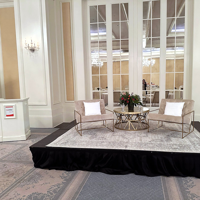 a coffee table and lounge chairs set up on stage with a podium nearby