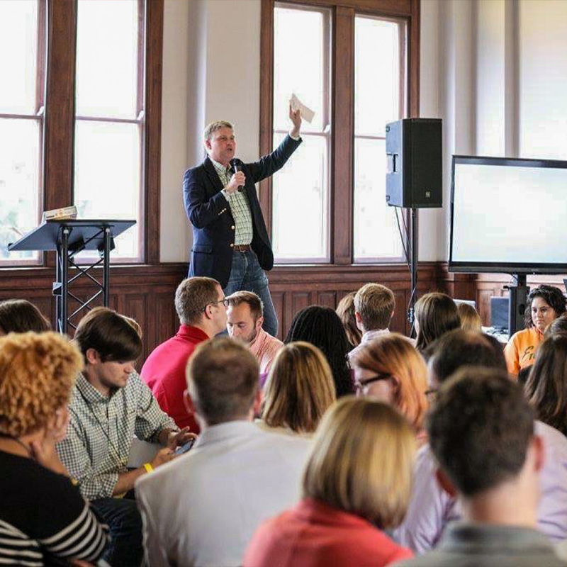 man gesturing on stage at a business training event