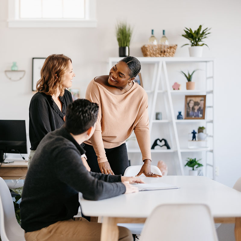 co-workers having an amiable conversation around a table in a modern office with natural lighting